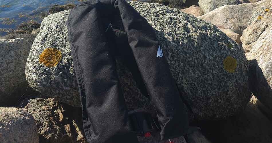 Collected and packed life jacket, lying next to a rock in sunny weather.